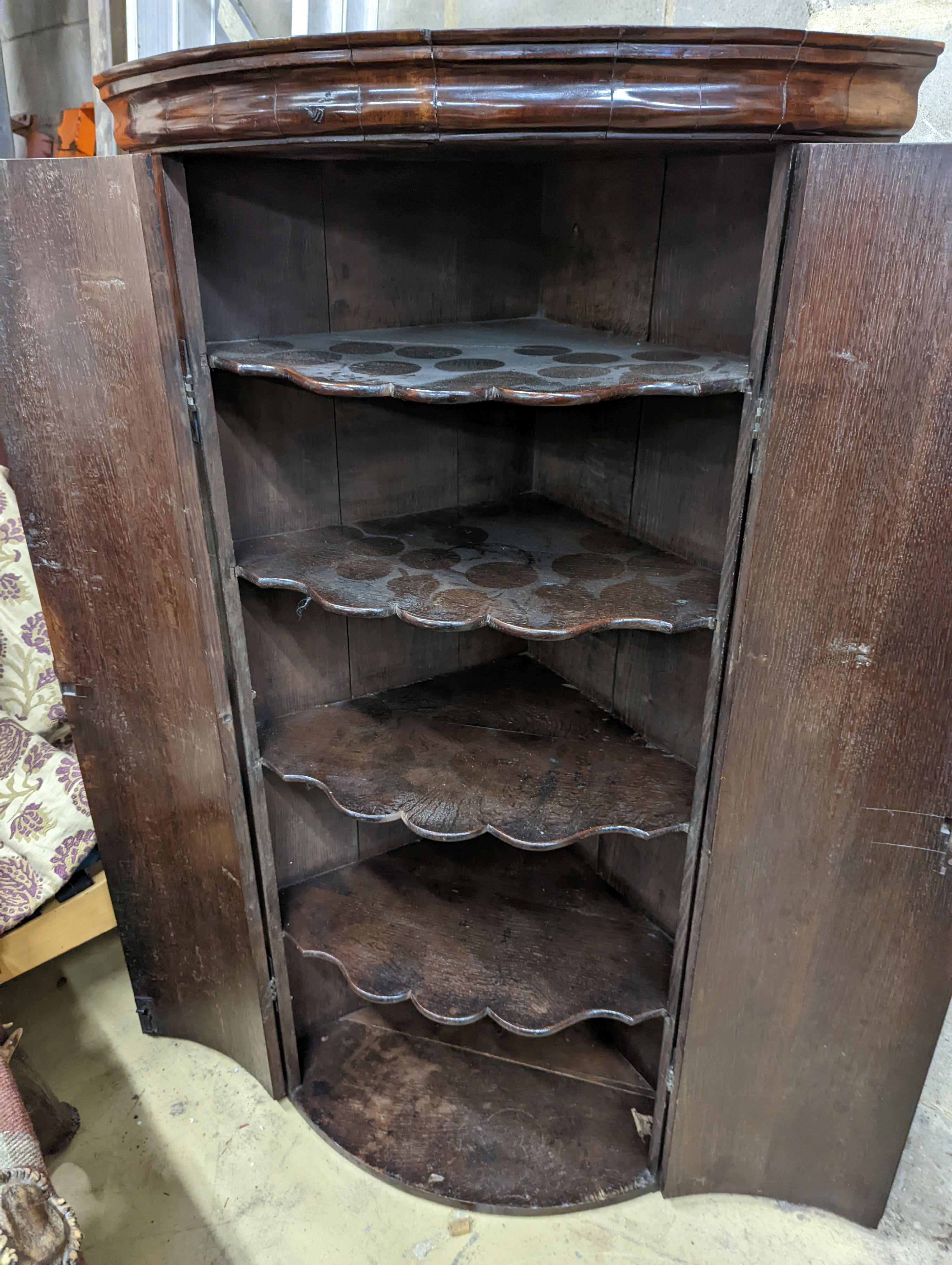 A George III oak bow-fronted hanging corner cabinet, width 73cm, depth 52cm, height 132cm